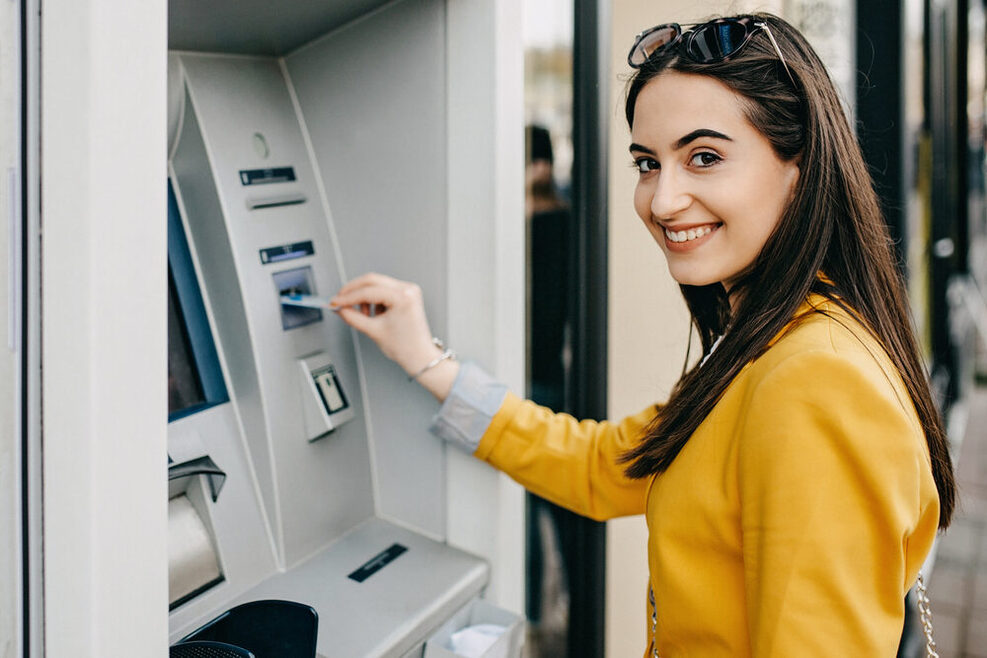A young Woman is using an ATM Machine.