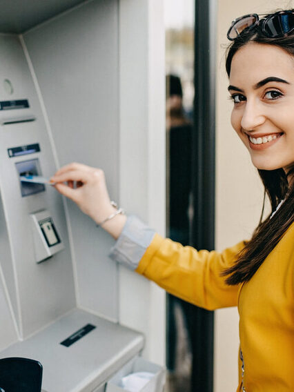 A young Woman is using an ATM Machine.