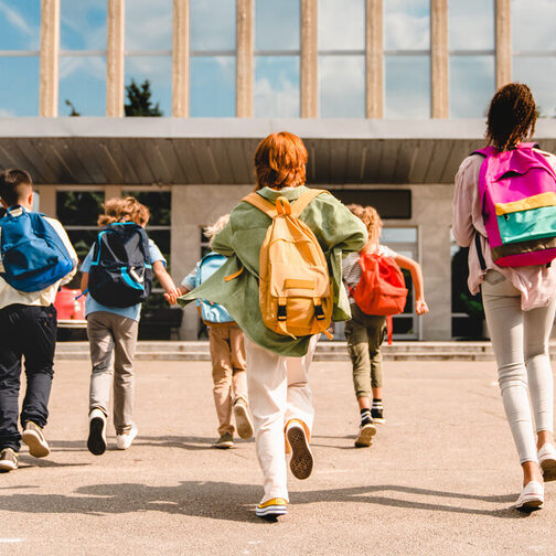Schoolkids walking towards a schoolbuilding.